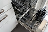A clean and empty stainless steel dishwasher open in a modern kitchen setting.